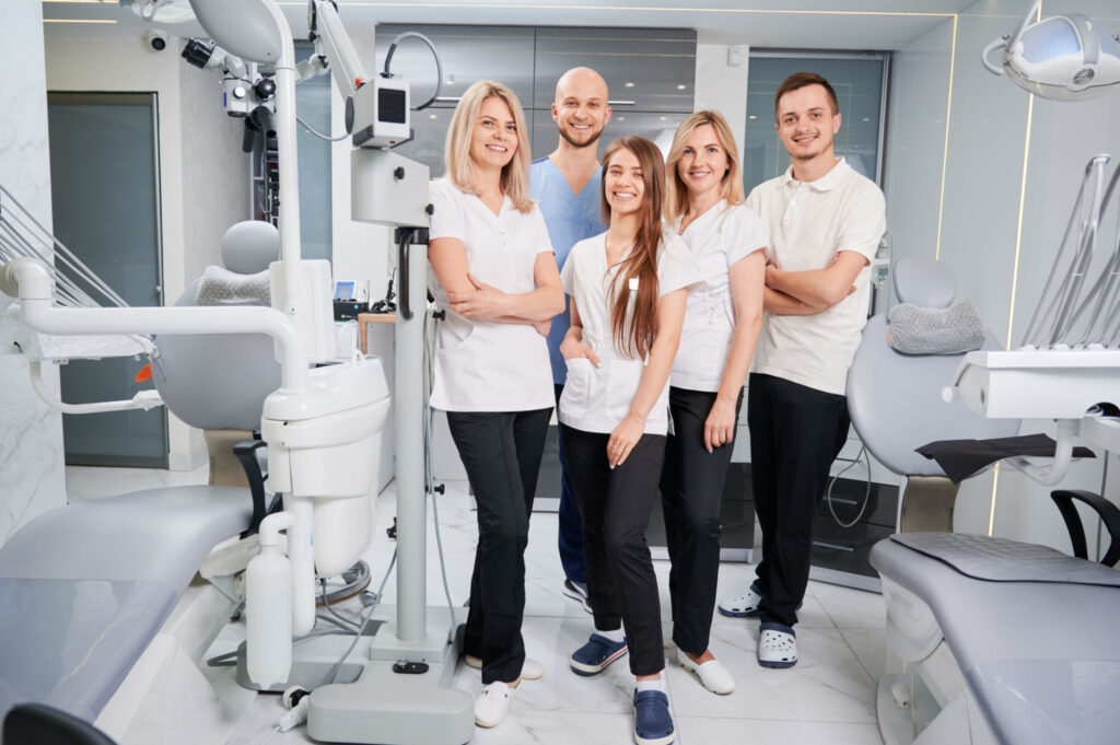 The professional medical team of Dental Clinic 24 Antalya posing in a modern treatment room with advanced dental equipment.
